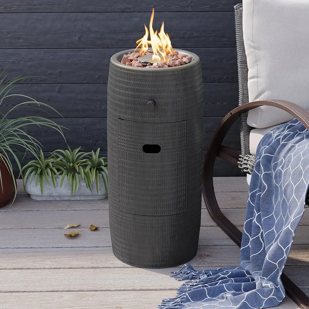 Modern column-style propane fire pit by COSIEST in dark grey, made of magnesium oxide with a lacquered finish, featuring a compact design, stainless steel burner bowl, red lava rocks, and hidden 1lb propane tank storage.